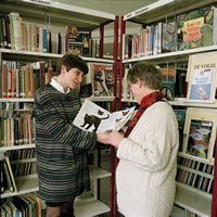 Foto: bibliotheekmedewerker geeft uitleg aan bezoeker.